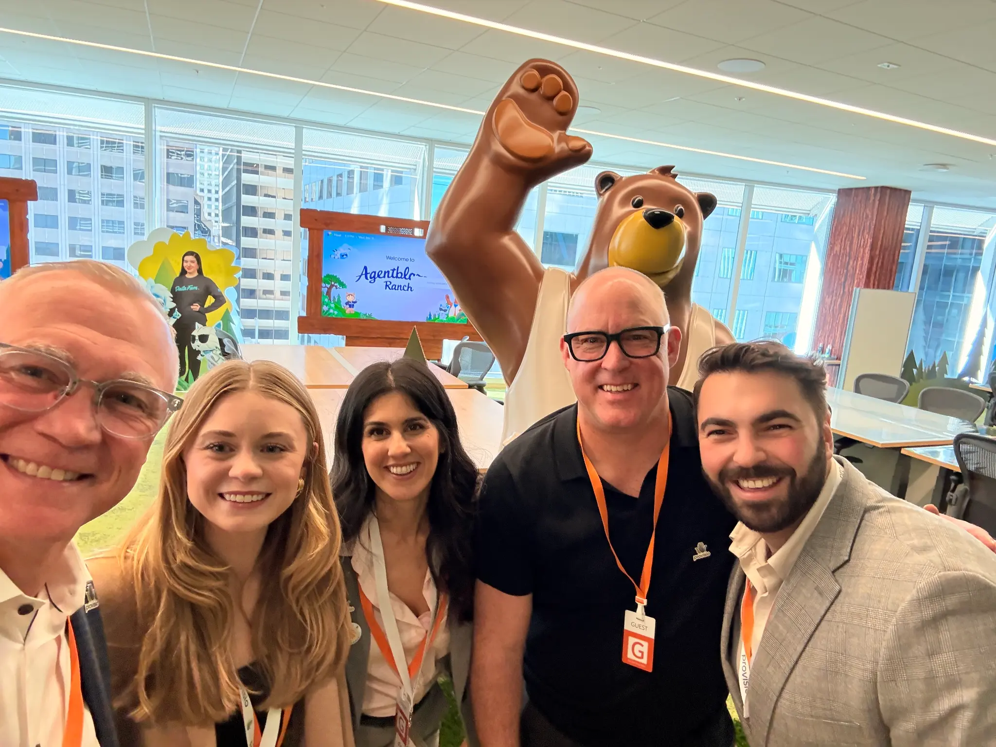 A group selfie of event attendees gathered inside a bright conference space.